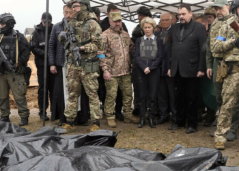 EU Commission President Ursula von der Leyen, center, looks at covered bodies of killed civilians in Bucha, on the outskirts of Kyiv, Ukraine, Friday, April 8, 2022. (AP Photo/Efrem Lukatsky)