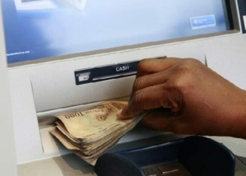 Depict image - A woman takes Nigerian Naira from a bank's automated teller machine (ATM)