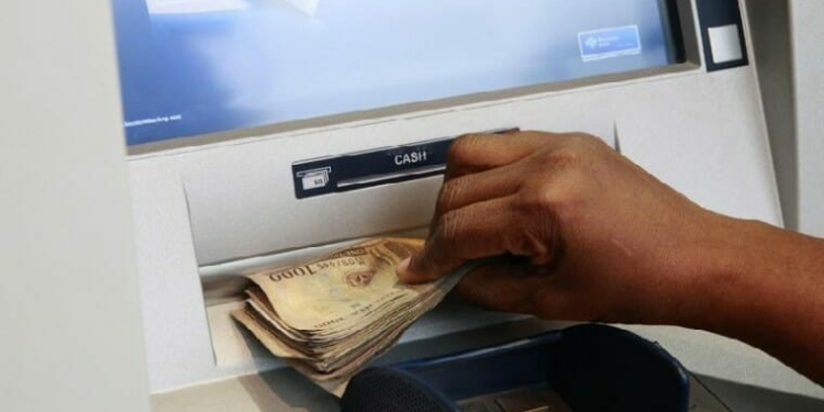 Depict image - A woman takes Nigerian Naira from a bank's automated teller machine (ATM)