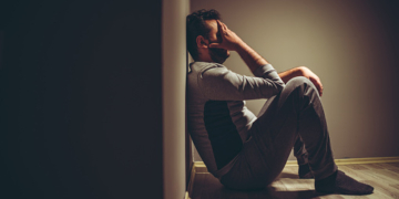 Young depressed man sitting on floor.