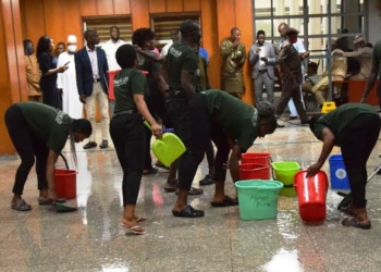 The National Assembly cleaners mopping the floor as rain flooded the lobby from a leaking roof that disrupted plenary session in Abuja yesterday. Photo Lucy Ladidi Ateko