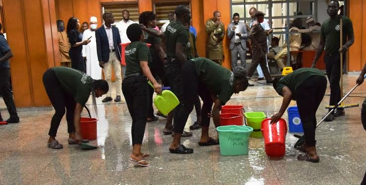 The National Assembly cleaners mopping the floor as rain flooded the lobby from a leaking roof that disrupted plenary session in Abuja yesterday. Photo Lucy Ladidi Ateko