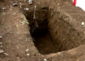 Zoom in on recently dug empty grave in the graveyard