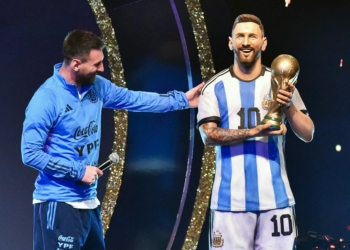 Argentina's forward Lionel Messi looks at a statue of himself during a tribute by Conmebol to the members of the Argentine national team for winning the Qatar 2022 World Cup, before the draw of the group phases of the Libertadores and Sudamericana football tournaments, at Conmebol's headquarters in Luque, Paraguay, on March 27, 2023. (Photo by NORBERTO DUARTE / AFP)
