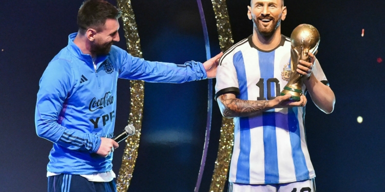 Argentina's forward Lionel Messi looks at a statue of himself during a tribute by Conmebol to the members of the Argentine national team for winning the Qatar 2022 World Cup, before the draw of the group phases of the Libertadores and Sudamericana football tournaments, at Conmebol's headquarters in Luque, Paraguay, on March 27, 2023. (Photo by NORBERTO DUARTE / AFP)