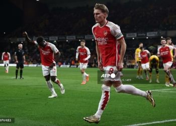 Arsenal's Norwegian midfielder #08 Martin Odegaard (C) celebrates after scoring their second goal during the English Premier League football match between Wolverhampton Wanderers and Arsenal at the Molineux stadium in Wolverhampton, central England on April 20, 2024. (Photo by HENRY NICHOLLS / AFP) / RESTRICTED TO EDITORIAL USE. NO USE WITH UNAUTHORIZED AUDIO, VIDEO, DATA, FIXTURE LISTS, CLUB/LEAGUE LOGOS OR 'LIVE' SERVICES. ONLINE IN-MATCH USE LIMITED TO 120 IMAGES. AN ADDITIONAL 40 IMAGES MAY BE USED IN EXTRA TIME. NO VIDEO EMULATION. SOCIAL MEDIA IN-MATCH USE LIMITED TO 120 IMAGES. AN ADDITIONAL 40 IMAGES MAY BE USED IN EXTRA TIME. NO USE IN BETTING PUBLICATIONS, GAMES OR SINGLE CLUB/LEAGUE/PLAYER PUBLICATIONS. /