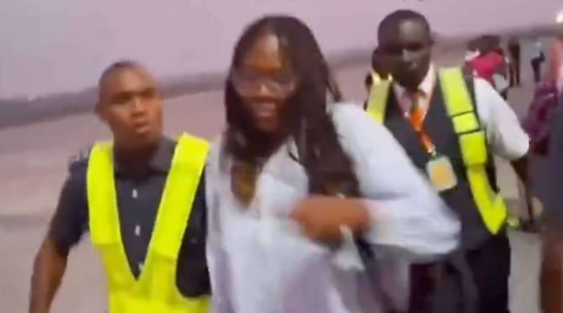 The passenger in white being escorted by airport officials