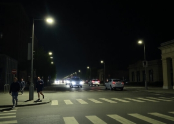 Pedestrians walking on city street under streetlights at night