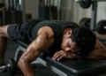 Exhausted person collapsing on gym bench after workout.