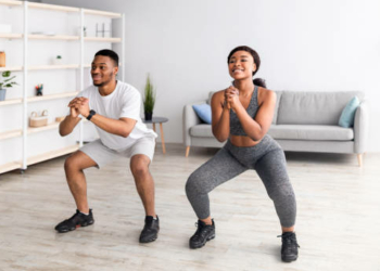 Strength workout concept. Fit black woman and her boyfriend doing squats together at home, panorama. African American couple having domestic training during covid-19 quarantine