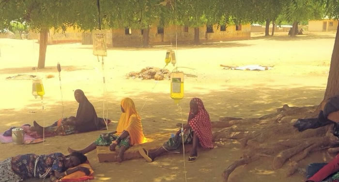 residents receiving drip under a tree