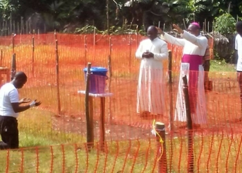 Photo of Catholic Bishop praying for Fr.Lucian Ambunga, priest who was infected with Ebola in Congo.