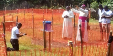 Photo of Catholic Bishop praying for Fr.Lucian Ambunga, priest who was infected with Ebola in Congo.