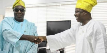 Visually impaired Akinyemi Andrew Elijah exchanging handshake with Governor Amosu