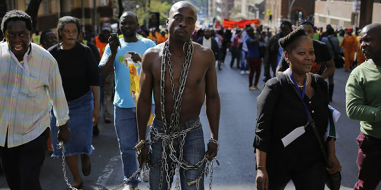 A man wearing chains walks with thousands of others during a march calling for an end to attacks against foreign nationals in Johannesburg, South Africa