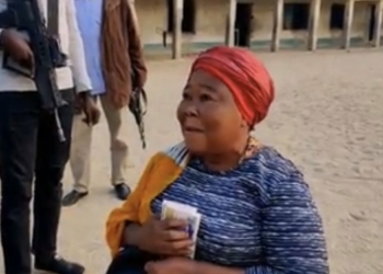The class teacher kneeling down as she receives cash gifts from Borno Governor