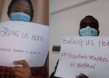 Some Nigerians in Wuhan holding placards inside their apartment