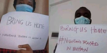 Some Nigerians in Wuhan holding placards inside their apartment