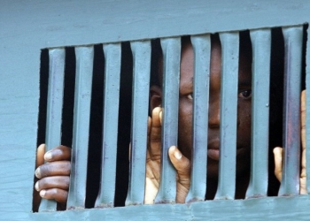 One of the men accused arrested for alleged vagabond peeks through tiny holes in black maria waiting to be taken to the prison after the hearing at the Tudun Alkali Area Sharia Court in Bauchi Tuesday 21 August, 2007. Eighteen men arrested for wearing female clothing, who had come to Bauchi from different states in the country for undisclosed reason  were brought to the Tudun Alkali Area Sharia Court to face trial for contravening the sharia penal code adopted in Bauchi and other states in northern Nigeria eight years ago.  The punishment if convicted is a year imprisonment and 20 lashes of cane for the culprit. AFP PHOTO / PIUS UTOMI EKPEI / AFP PHOTO / PIUS UTOMI EKPEI