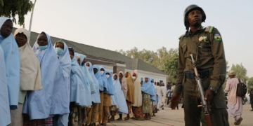A police officer stands next to a group of girls previously kidnapped from their boarding school in northern Nigeria. AFP