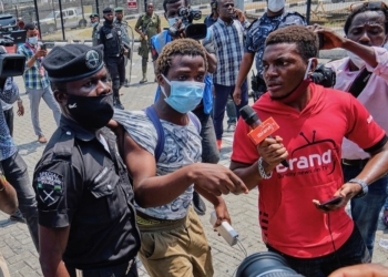 A journalist (in red) covers the arrest of a protester by the police, during a demonstration in Lagos. Nigeria, 13 feb, 2021; the journalist was also harassed. Adeyinka Yusuf/Majority World/universal images group via Getty Images