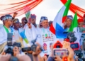 Peter Mbah, Enugu governor, waves the APC flag and broom during his official defection to the ruling party