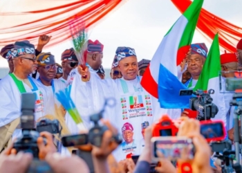 Peter Mbah, Enugu governor, waves the APC flag and broom during his official defection to the ruling party