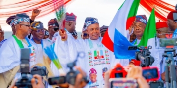 Peter Mbah, Enugu governor, waves the APC flag and broom during his official defection to the ruling party