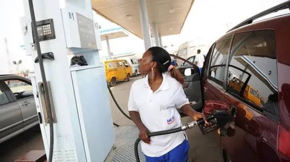 Nigerian motorist refuelling a car at a petrol station while checking the fuel dispenser meter